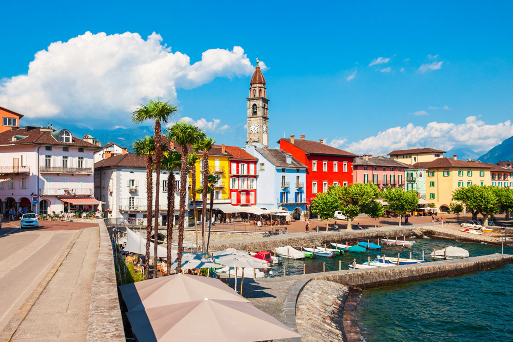 Ticino kantonunda Ascona limanı ve renkli cepheli tarihi binaların manzarası